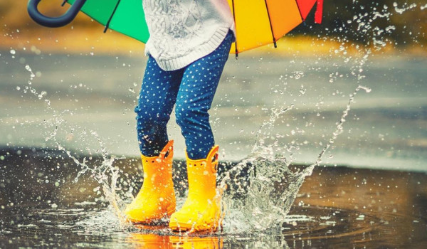 Girl in wellies splashing in a puddle